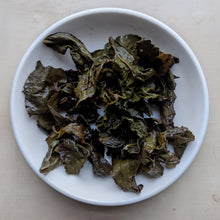 Spent leaves from Honeybug organic oolong tea in a small dish